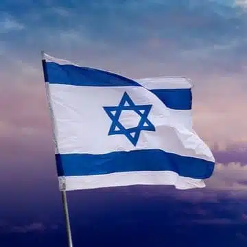 Israeli flag waving under a cloudy sky.